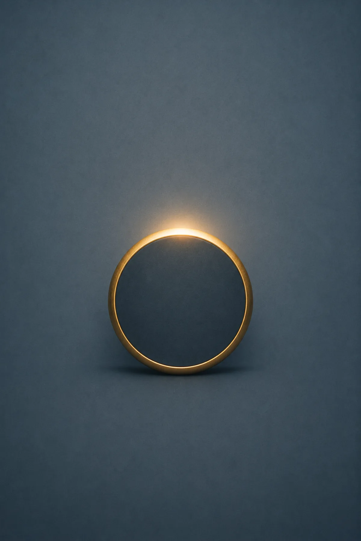 Una alianza dorada cuyo interior forma un eclipse total sobre un fondo azul grisáceo.